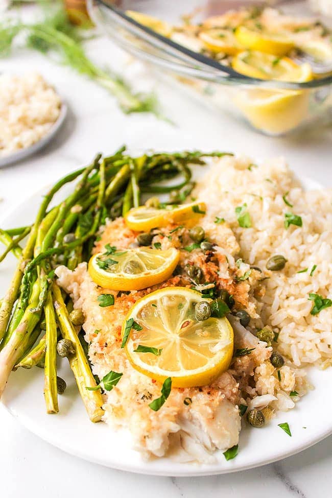parmesan crusted tilapia on a white plate with asparagus and rice