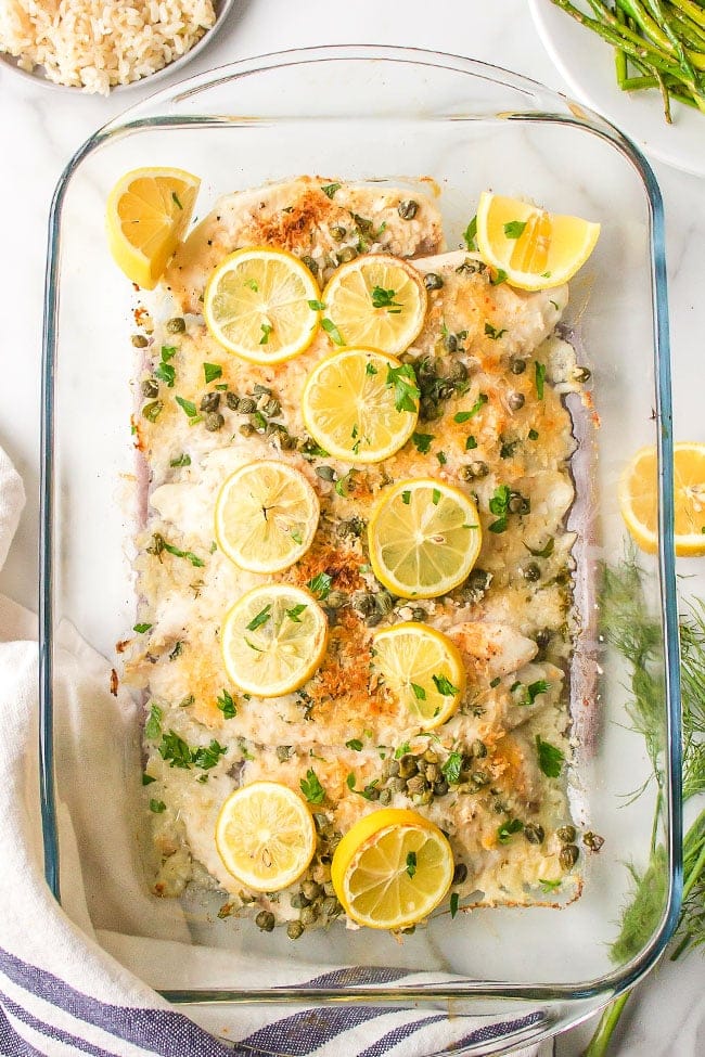 oven baked tilapia in a baking dish with fresh lemon slices