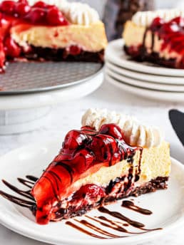 Slice of cherry cheesecake with brownie crust on a white plate