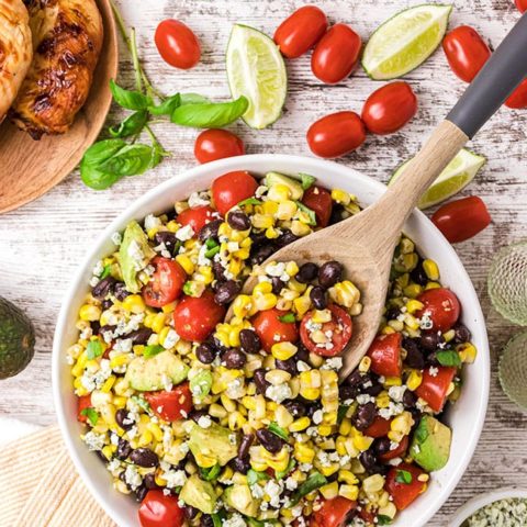fire roasted corn and black bean salad in a bowl with serving spoon