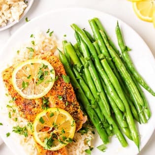 Baked salmon with lemon slices plated with rice and green beans
