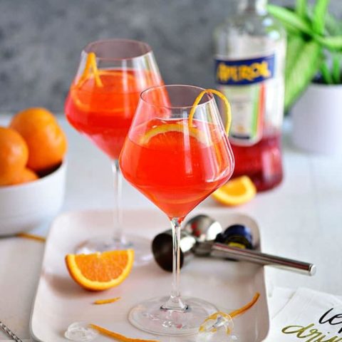 Italian Aperol cocktail in wine glasses with fresh oranges