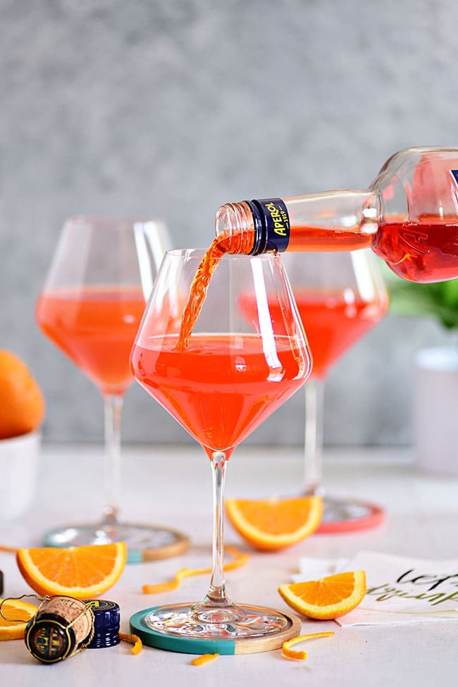 Pouring Aperol prosecco in a wine glass