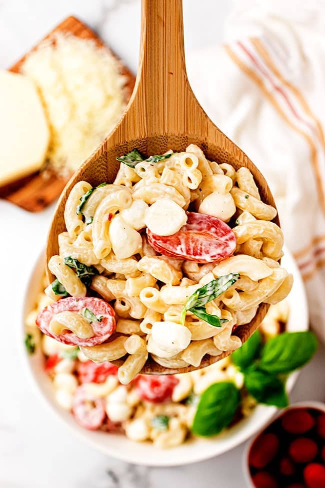 creamy Caprese Macaroni Salad on a wooden spoon