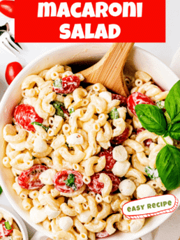 Creamy Caprese Macaroni Salad in a white bowl with a wooden spoon
