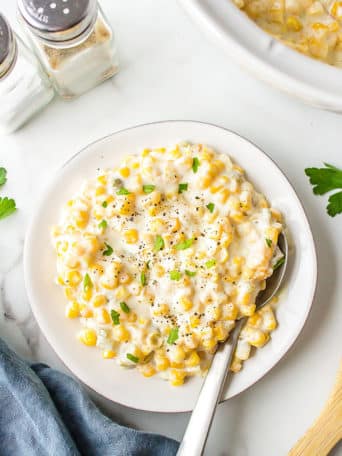 Easy Cream Cheese Corn on a plate and by a slow cooker