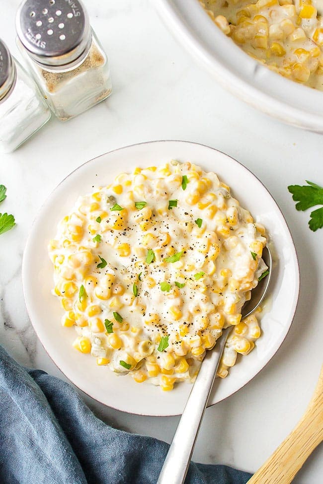 Easy Cream Cheese Corn on a plate and by a slow cooker