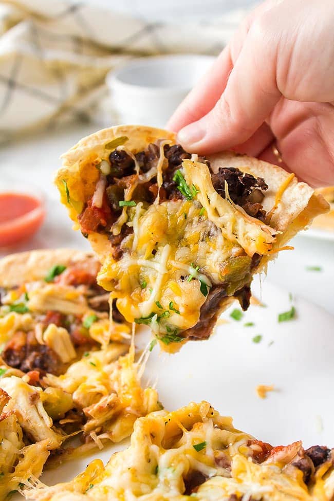 hand holding a slice of homemade Mexican pizza