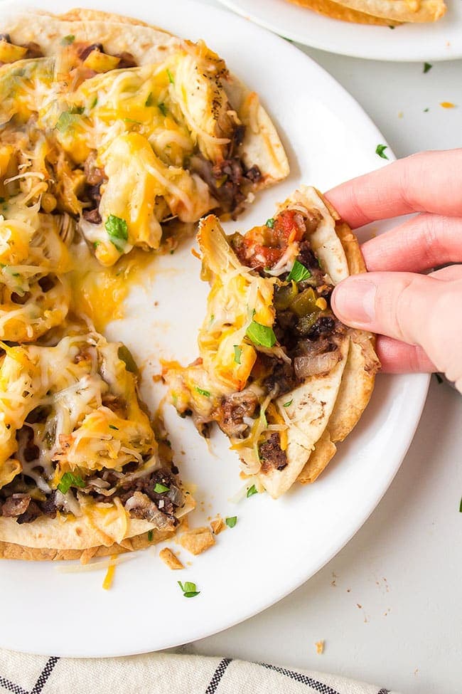 hand grabbing a slice of Mexican Pizza 