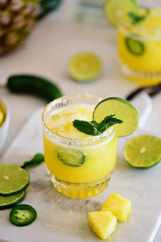 Spicy Pineapple Margarita in a glass with mint, fresh lime and jalapeño slices