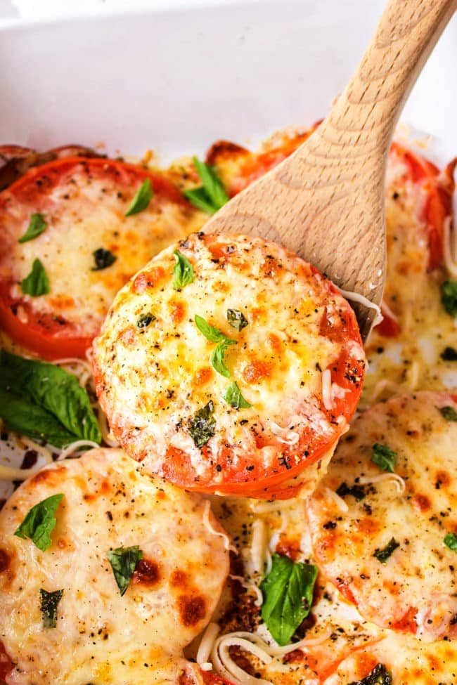 baked tomatoes with mozzarella served with a wooden spoon