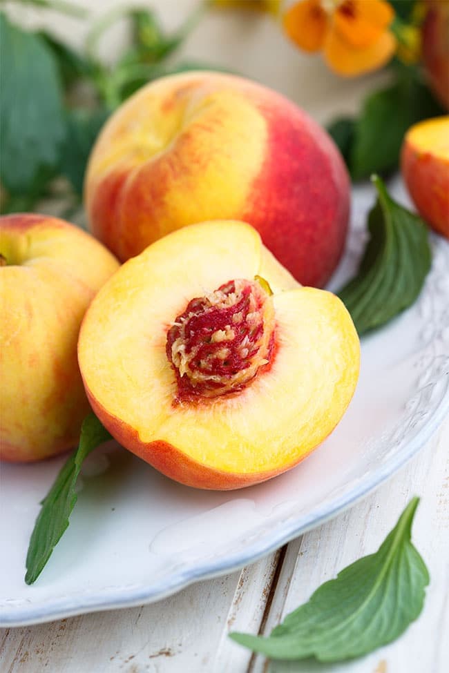 fresh peaches on a plate with leaves