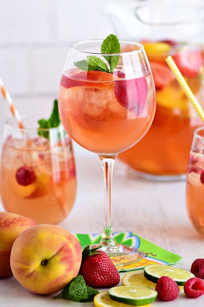 PEACH SANGRIA with Rosé in a stemmed wine glass with fresh fruit and mint