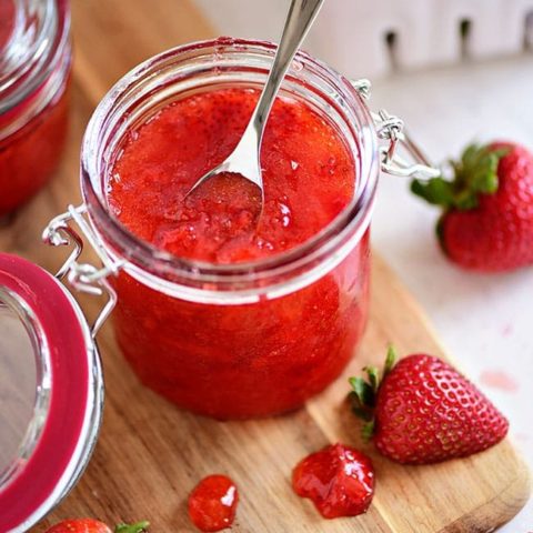 an open jar of no-cook strawberry jam with a spoon