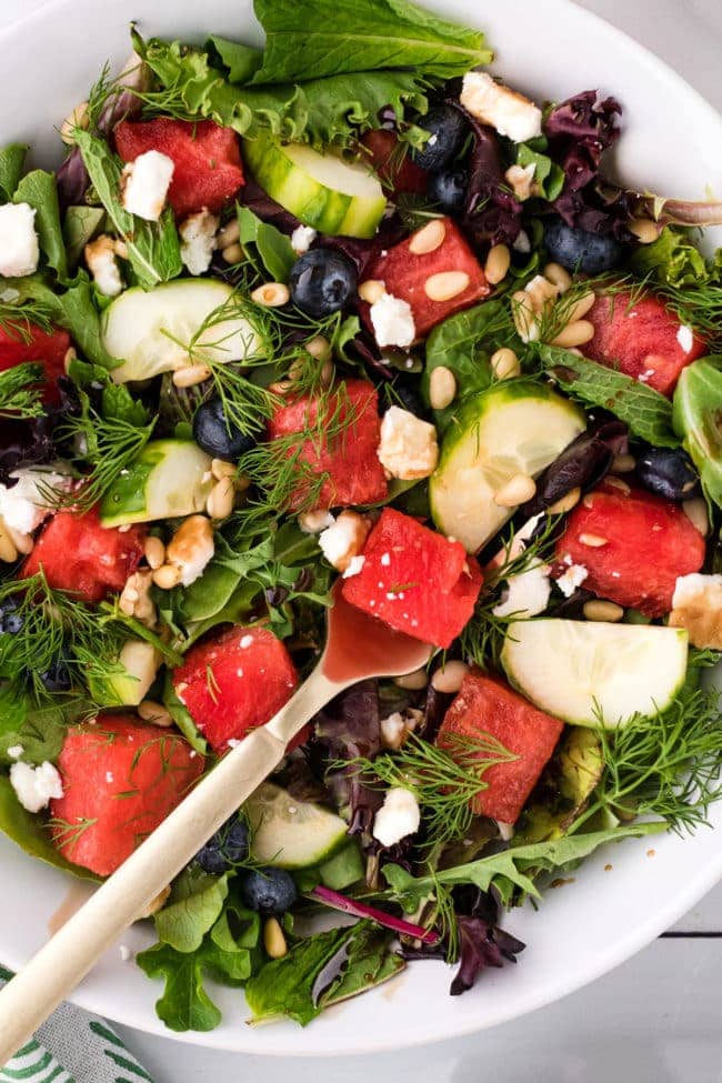 close up of watermelon salad on a fork in a white bowl