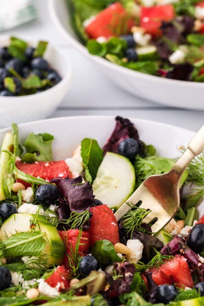 close up of watermelon salad in a bowl with a fork