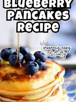 syrup being poured over a stack of blueberry pancakes