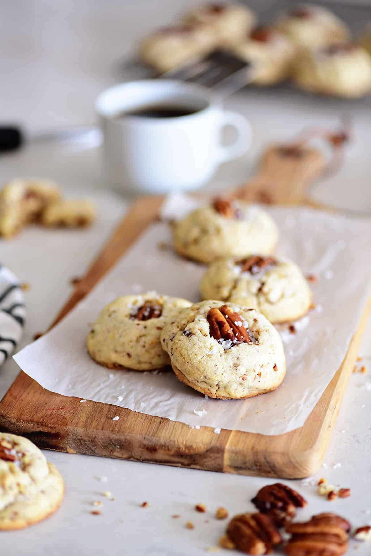 Butter Pecan Cookies on a wood board with a cup of coffee