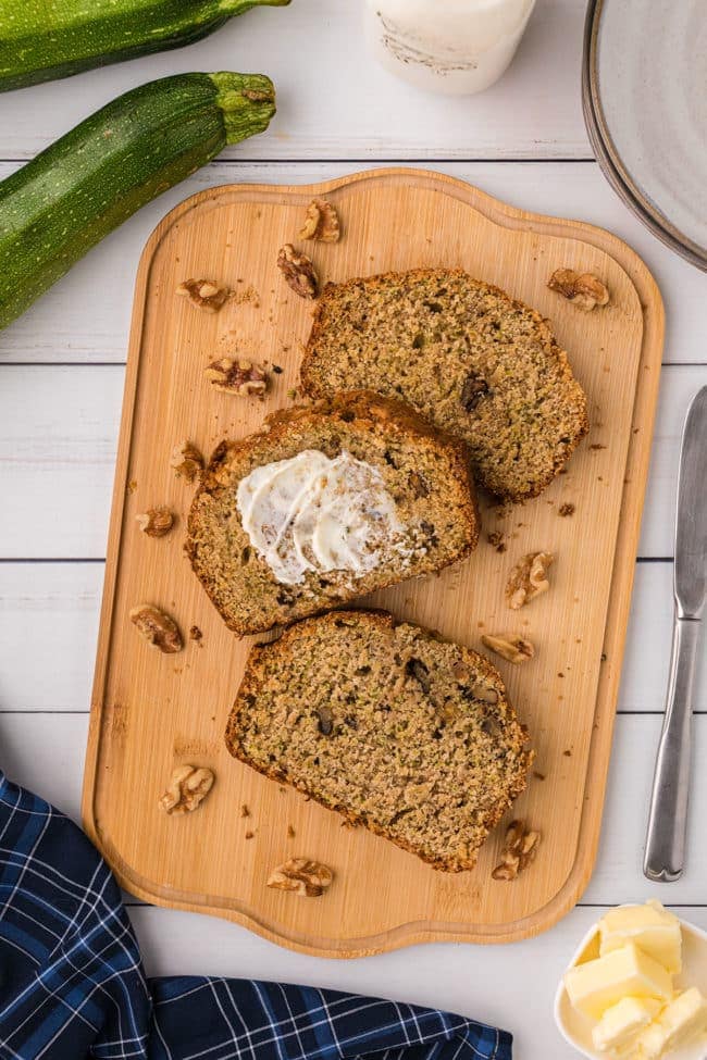 Three slices of zucchini bread with walnuts on a cutting board