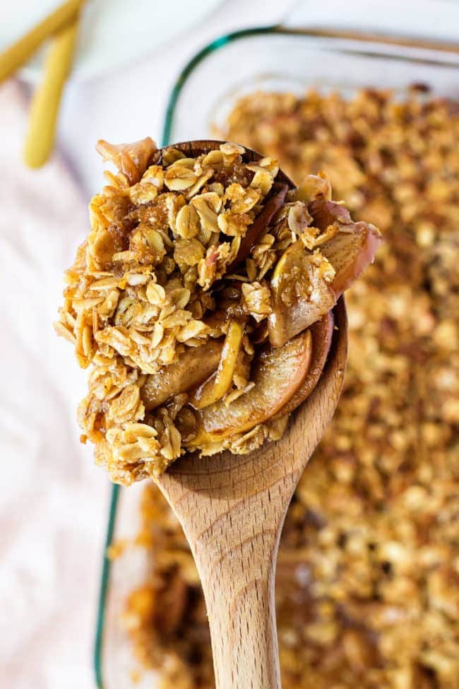 Easy apple crisp in a glass baking dish scooped out with a wooden spoon