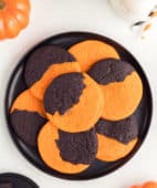A black platter stacked with Orange and Black Halloween Cookies