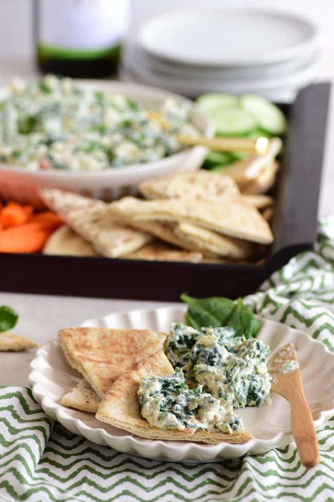 Creamy spinach dip on a tray with veggies and chips