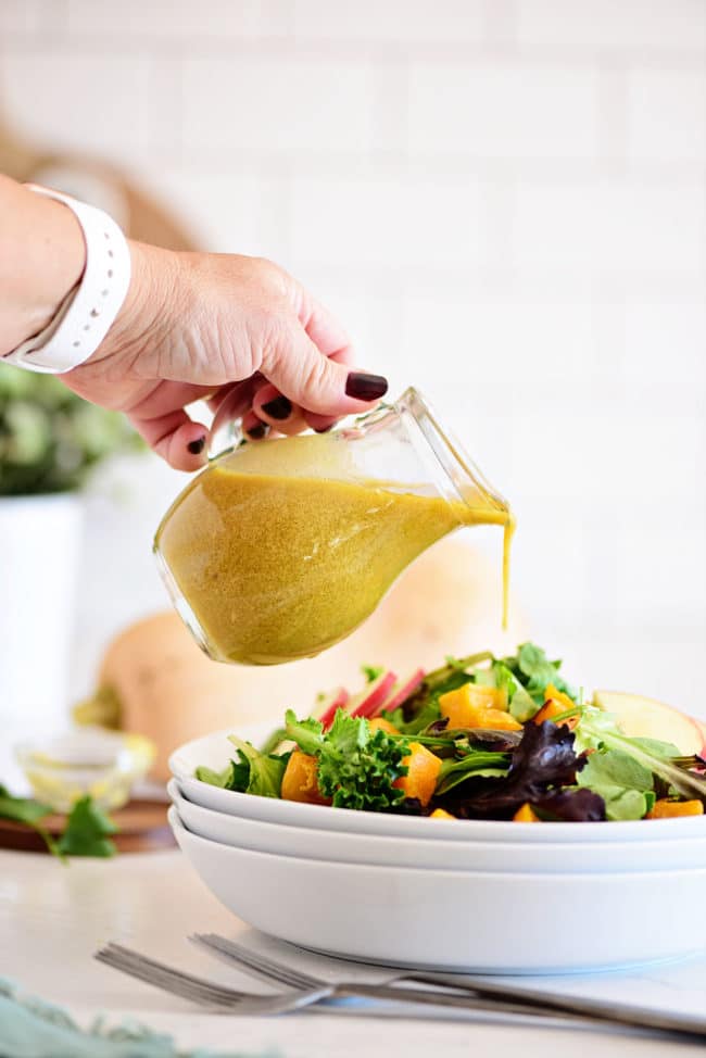 pouring Homemade Dijon mustard dressing on a salad