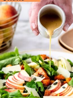 harvest salad with apple slices and dressing being poured over top