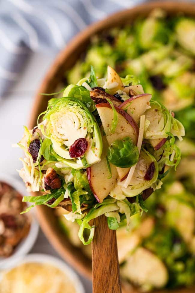 Brussles sprouts salad on a large wooden spoon over a bowl