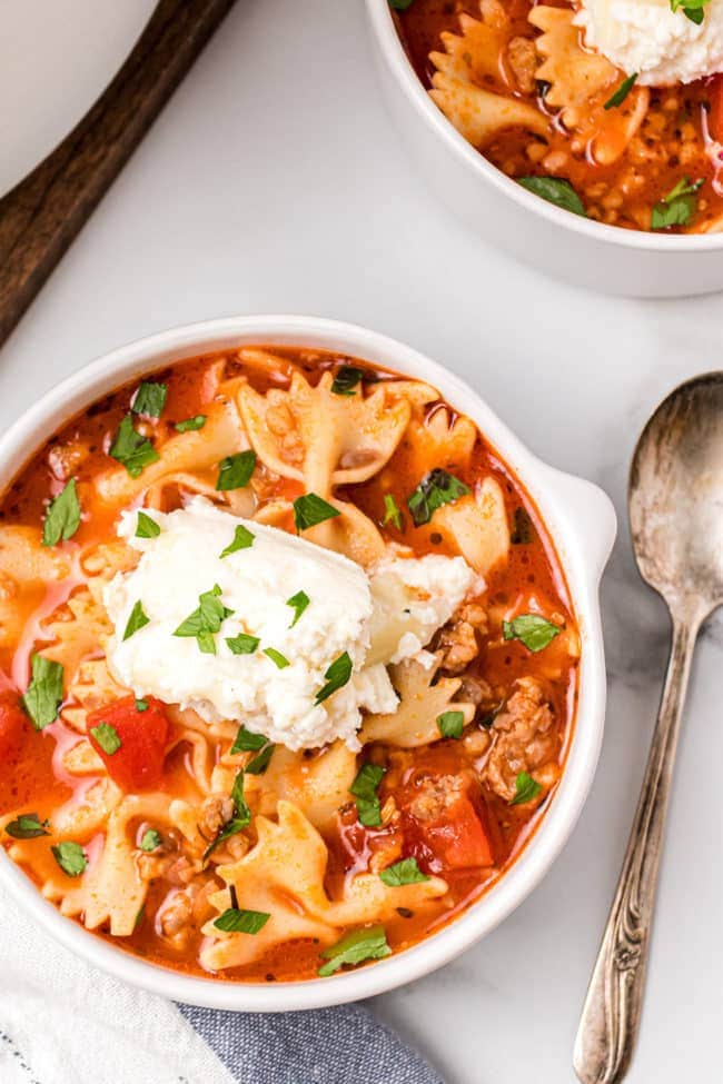 A bowl of lasagna soup with cheese on top