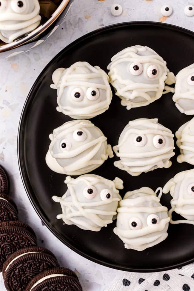 Easy Mummy Oreo Truffles on a black plate for halloween