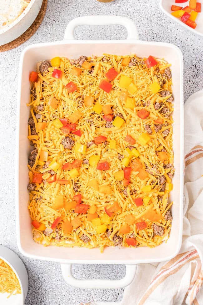 layering the egg casserole with cheese and veggies