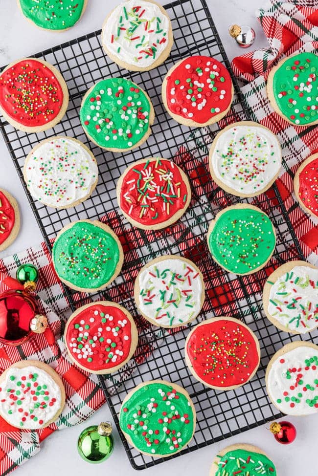 Holiday frosted sugar cookies on a cooling rack with a Christmas napkin