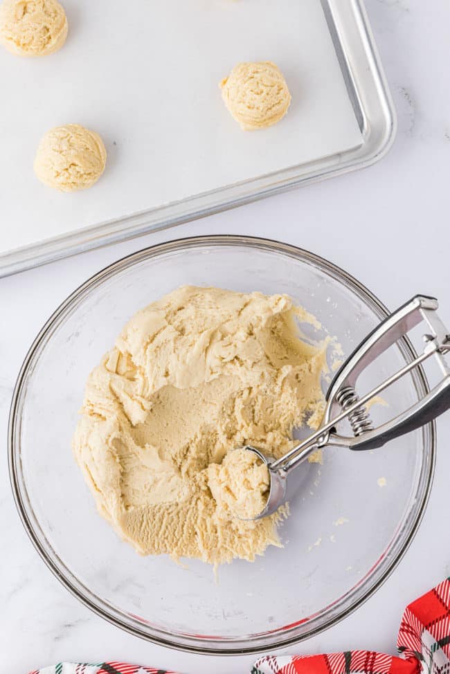 cookie dough in a glass bowl with a cookie scoop