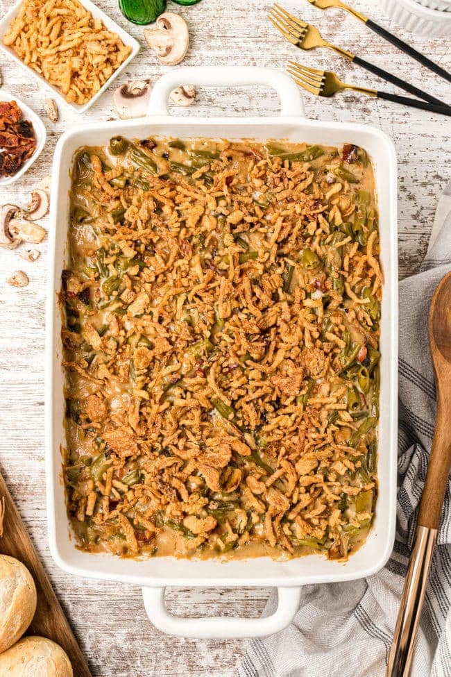 green bean casserole with bacon and fried onion in a white baking dish