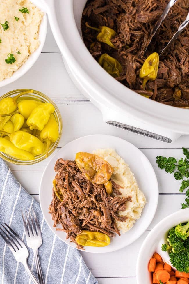 pot roast with pepperoncini and mashed potatoes on a plate by a slow cookier