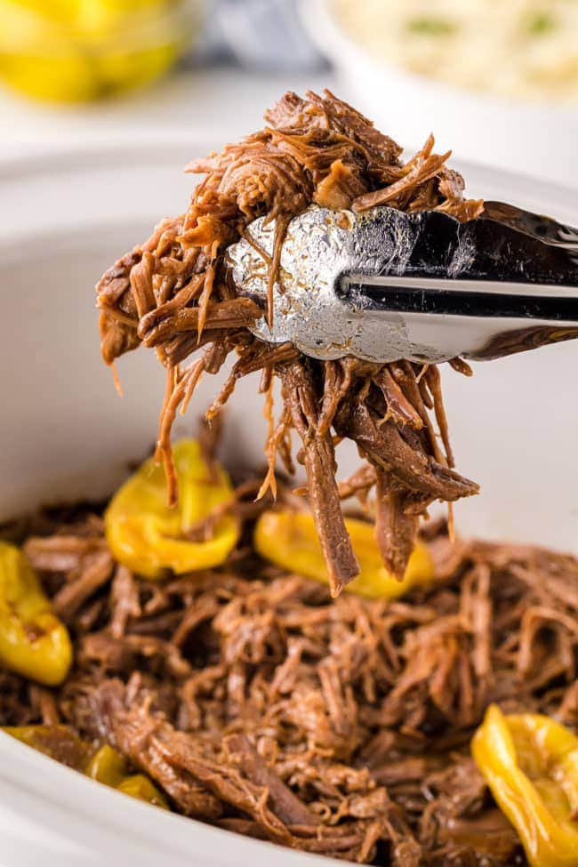 tongs holding a pile of beef pot roast