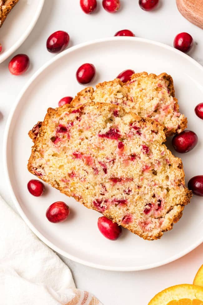 2 slices of Orange Cranberry Bread on a plate with fresh cranberries