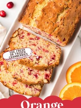 Sliced loaf of cranberry bread with fresh cranberries and orange slices