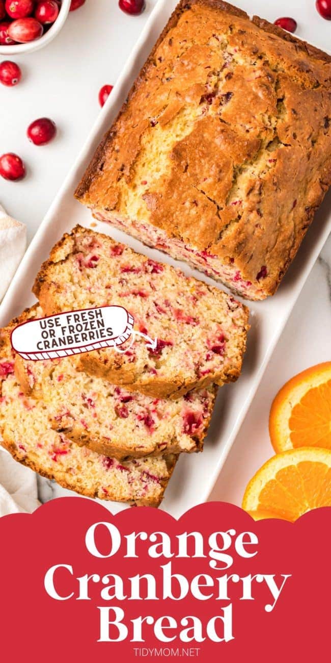 Sliced loaf of cranberry bread with fresh cranberries and orange slices