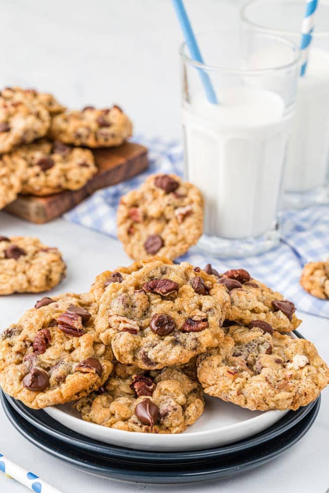 a plate full of cookies with a glass of milk and a straw.