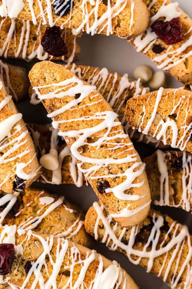 a pile of biscotti with white chocolate drizzle on a counter