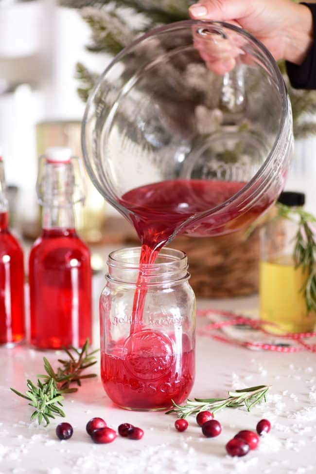 filling a mason jar with cranberry vodka