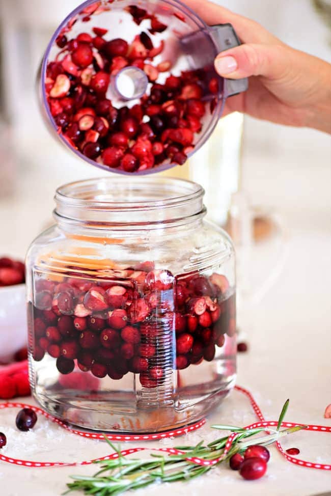 putting chopped cranberries in jar with vodka