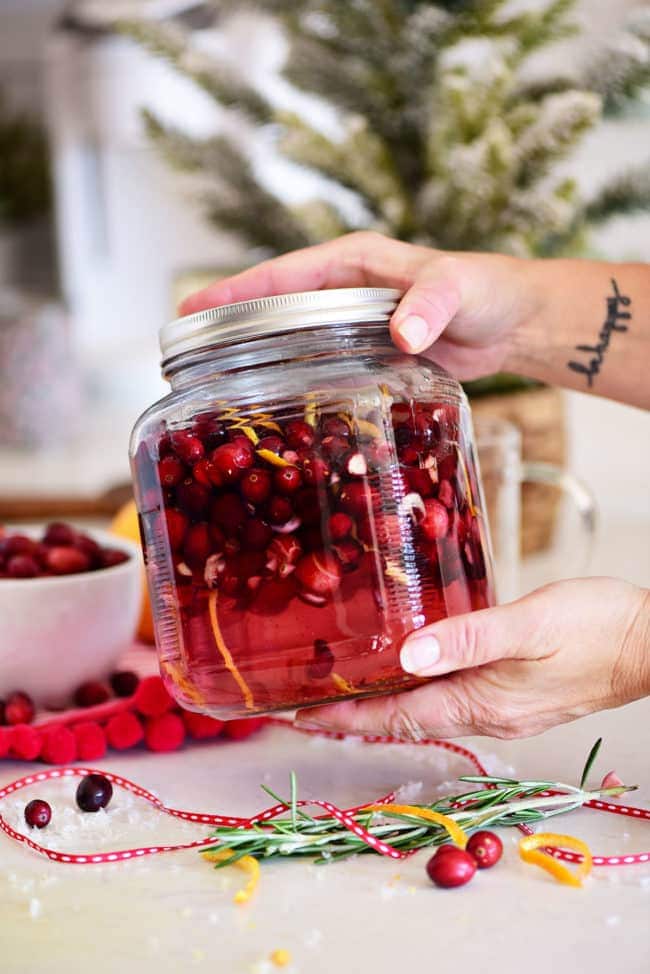 shaking a jar of cranberries and vodka to infuse