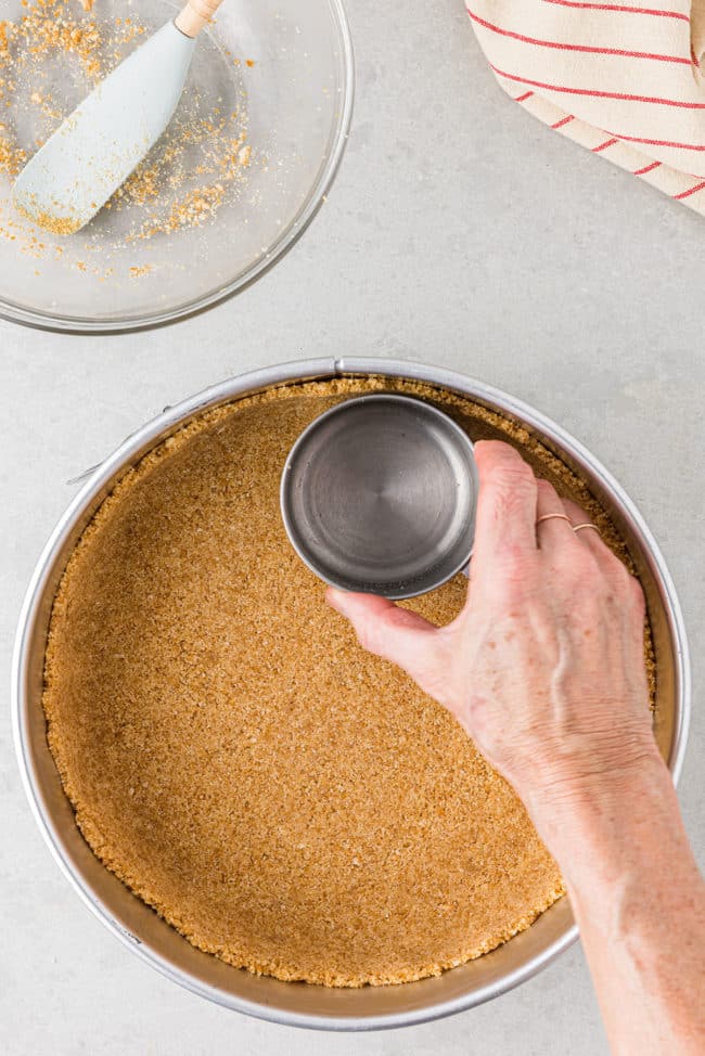 pressing out a cookie crust in a pan.