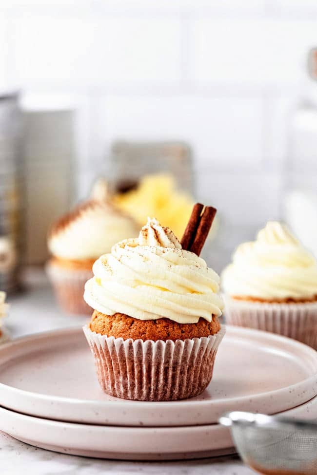 cupcake with buttercream piled on top with a cinnamon stick for garnish