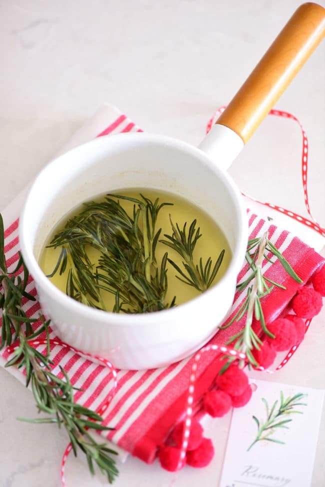 homemade simple syrup in a white saucepan with fresh rosemary
