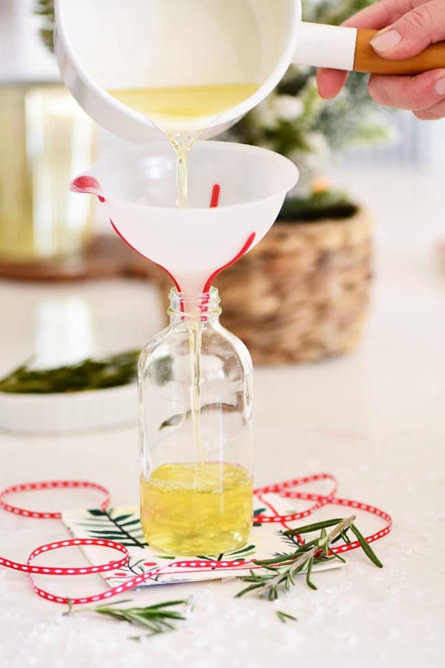 pouring homemade simple syrup in a bottle with a funnel
