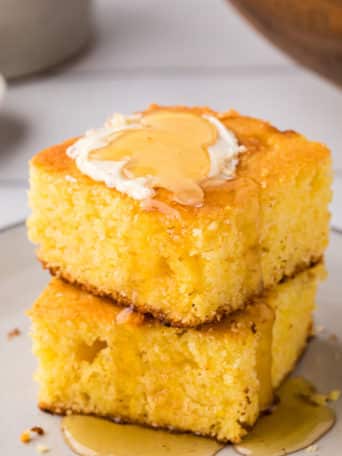 2 servings of cornbread stacked and topped with butter and honey